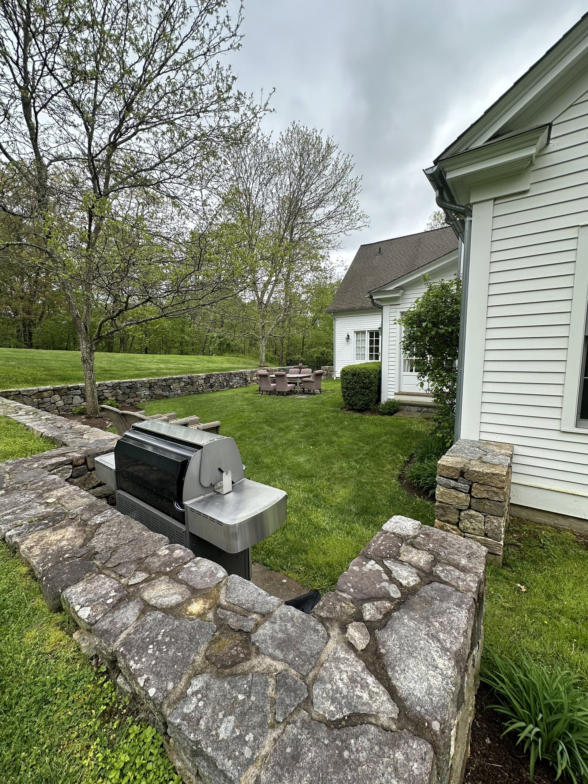 Stone retaining wall with built-in grill area and lawn